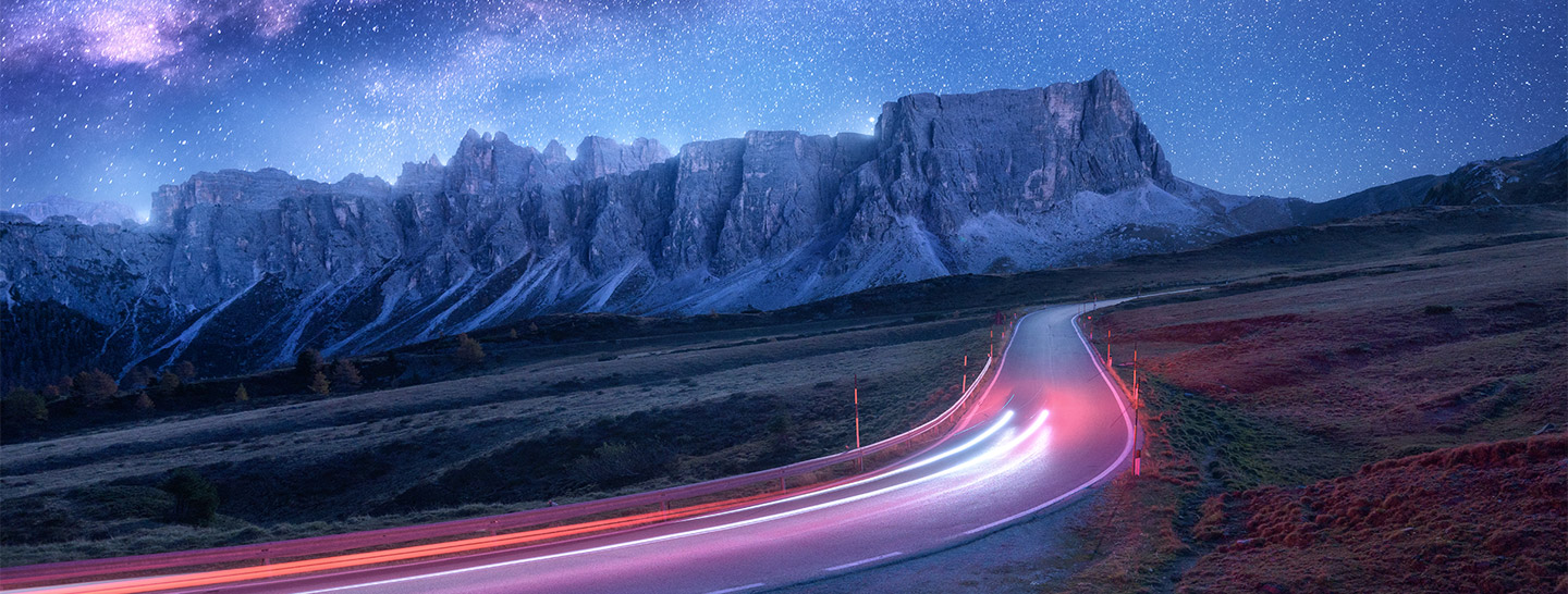 Una strada di notte in una zona di montagna con fasci di luce 